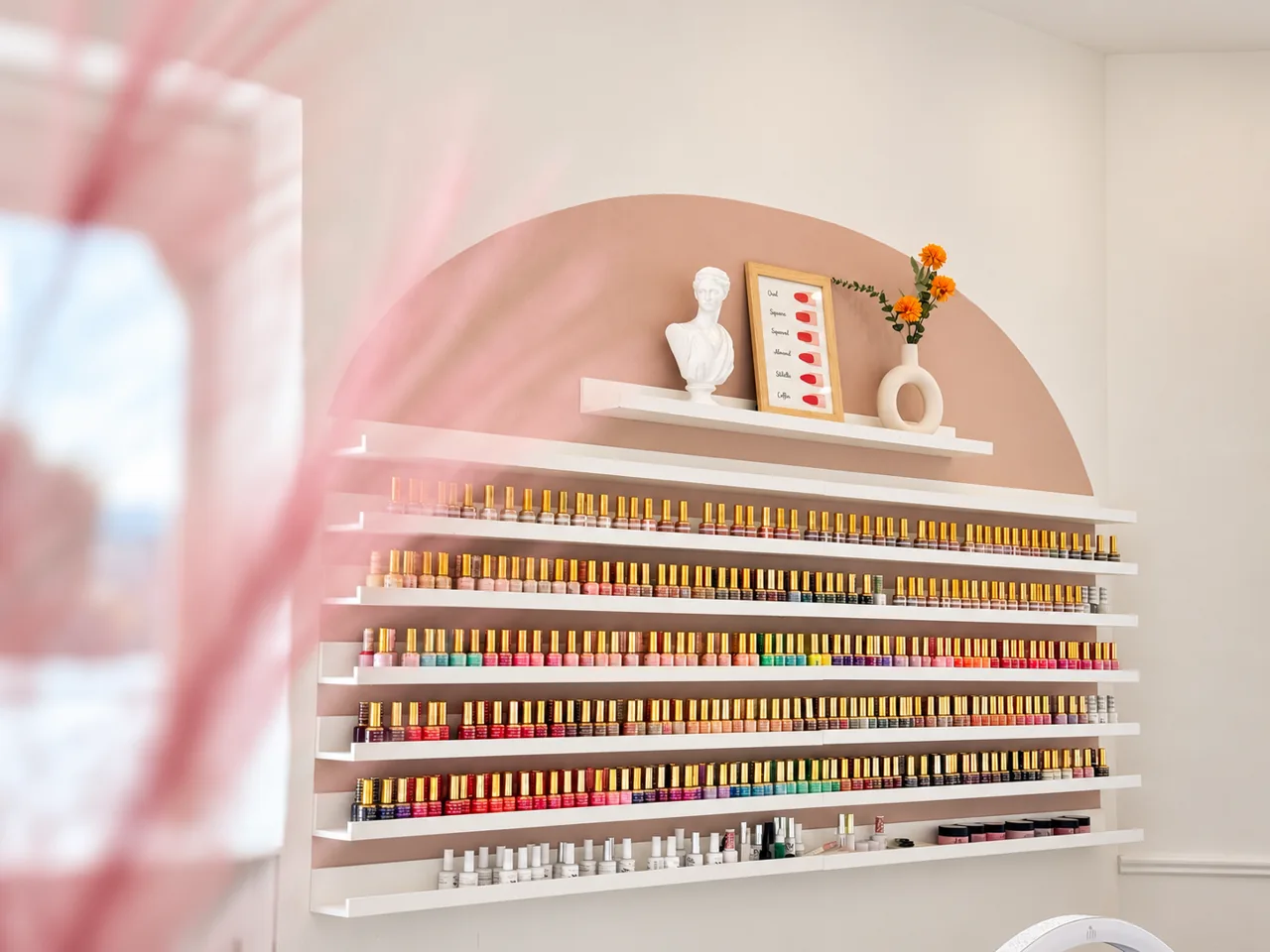 Rows of nail colours beneath a blush arch inside Havana